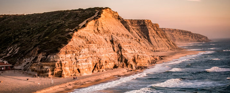 A sandy beach with ocean waves, ideal for surfing.