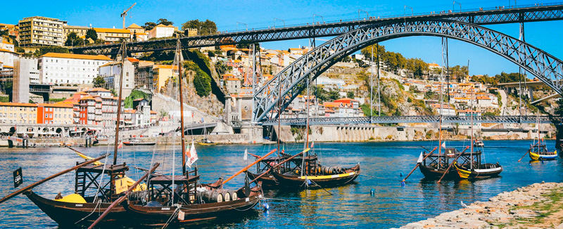 vista para o rio douro no porto com os barcos a navegar e a emblemática ponte dom Luís I