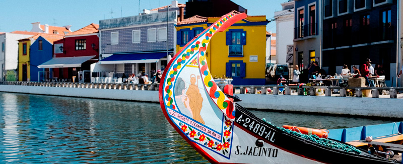 Colorful front of a moliceiro boat on the Ria de Aveiro with colorful houses in the background