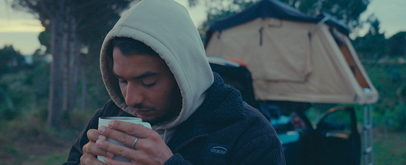 Miguel Blanco com roupa de inverno a segurar numa caneca branca prestes a beber