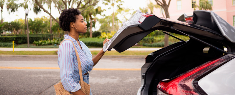 woman on a summer's day closing the boot of a car
