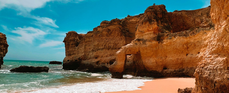 vista aérea de praia com agua cristalina e calma e pessoas a passear na areia