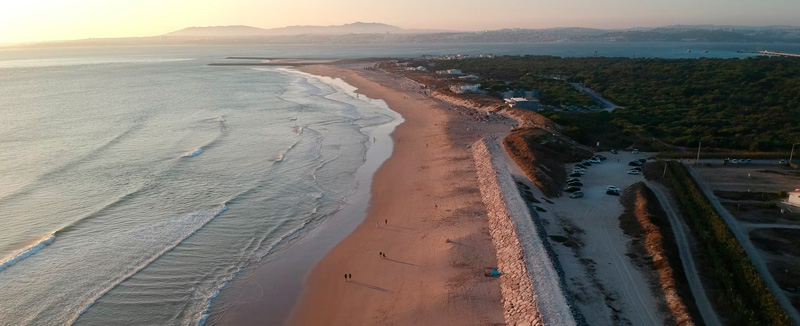Aerial view of a beach in Portugal with golden sand and blue sea, perfect for road trips along the Portuguese coast