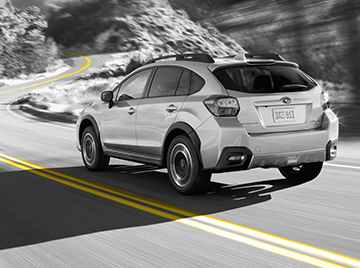 black and white image of subaru driving with yellow line on road